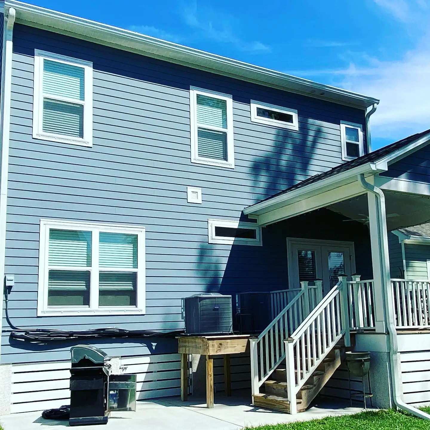 Back of a blue two-story home with white gutters and downspouts around the porch. Gutter Installation in Bluffton, SC by A&A Island Services