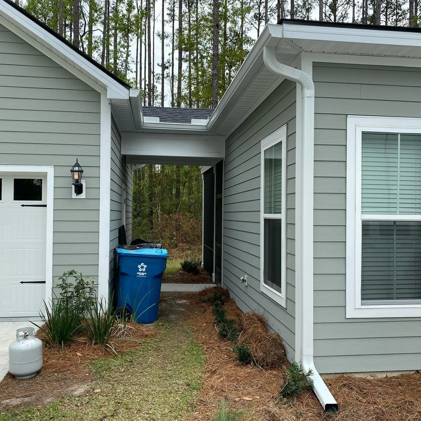 Breezeway between two gray home sections with white gutters and downspouts. Gutter Guards in Hardeeville, SC by A&A Island Services