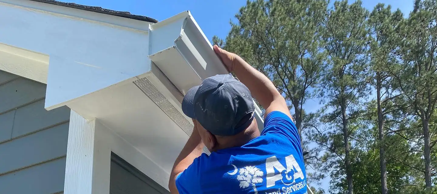 A&A crew member fitting a white gutter under a roof eave. Gutter installation in Bluffton, SC by A&A Island Services
