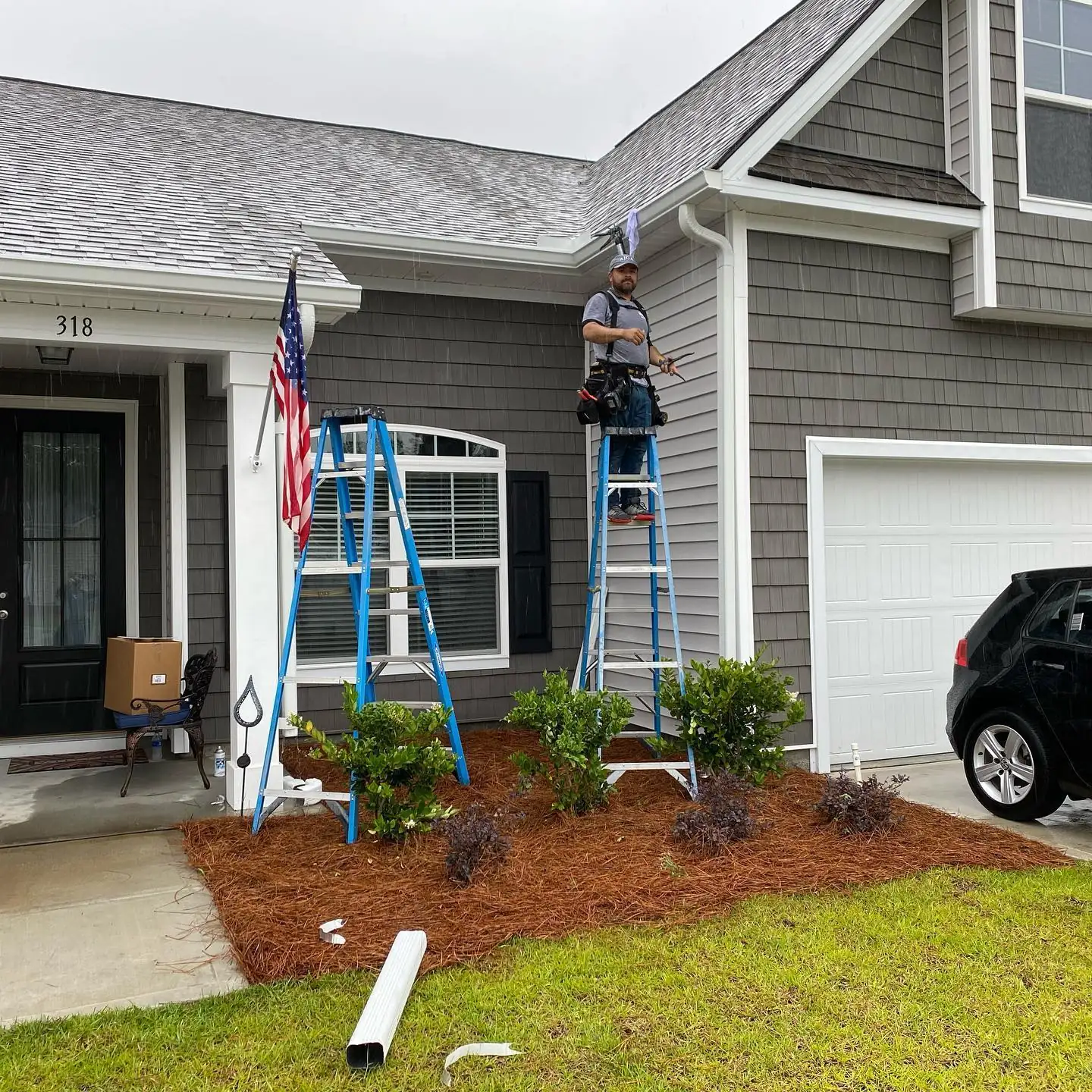 Two A&A crew members on ladders installing gutters on a gray home. Gutter cleaning, repair and installation in Bluffton, SC by A&A Island Services