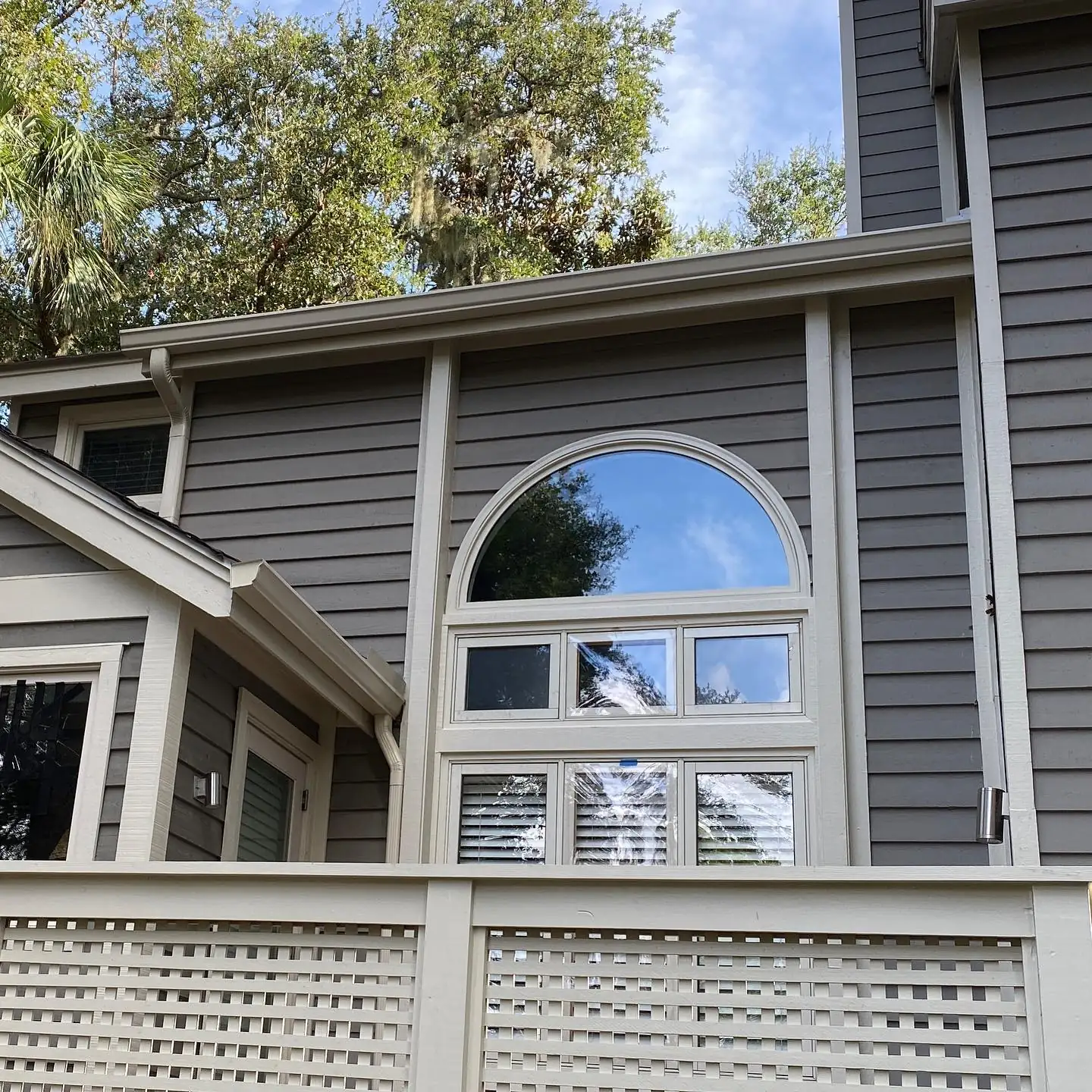 Gray two-story home with an arched window and gutters. Gutter services in Sea Pines, SC by A&A Island Services