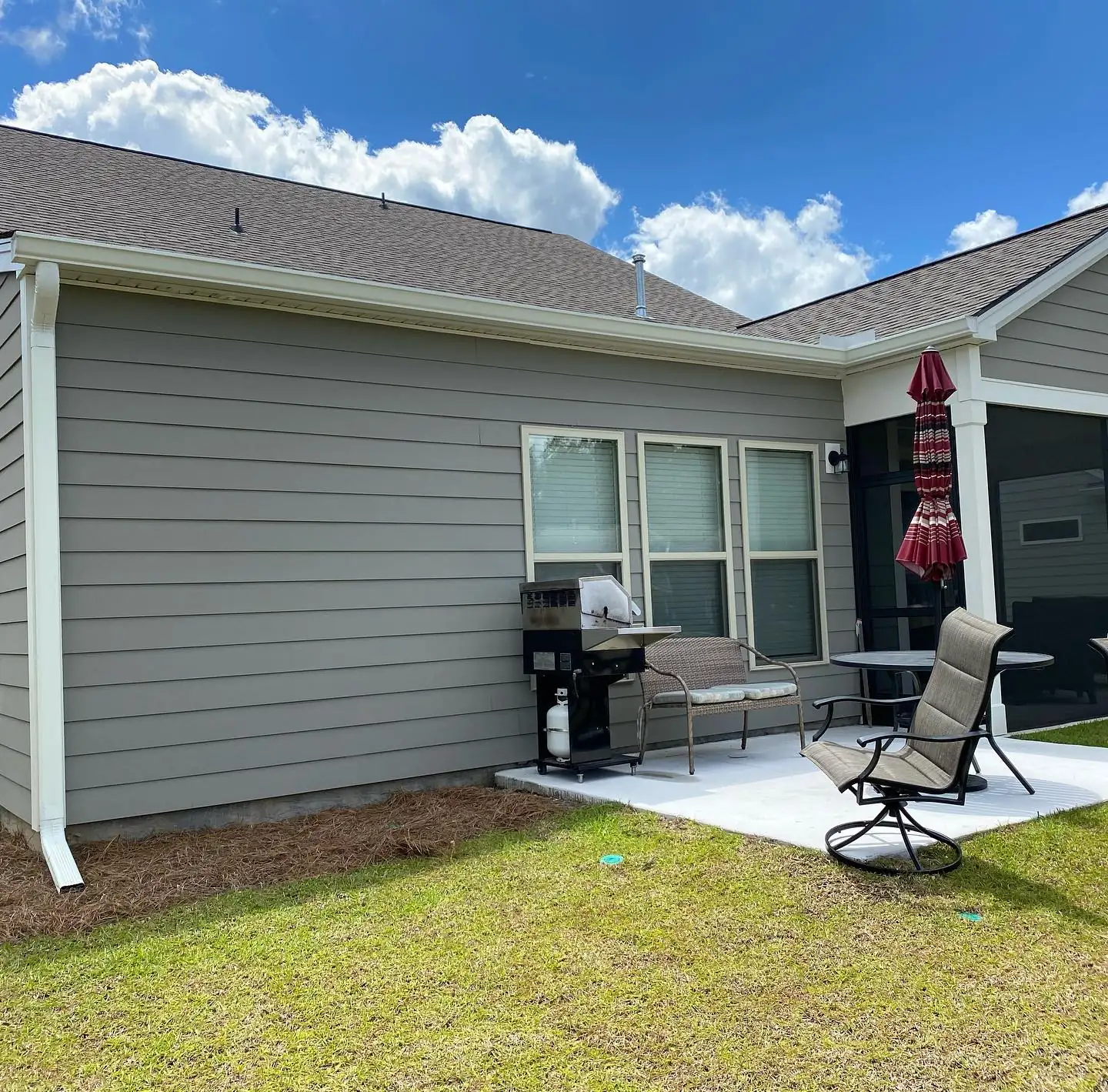 Gray home with a white downspout beside a back patio. Gutter services in Pritchardville, SC by A&A Island Services