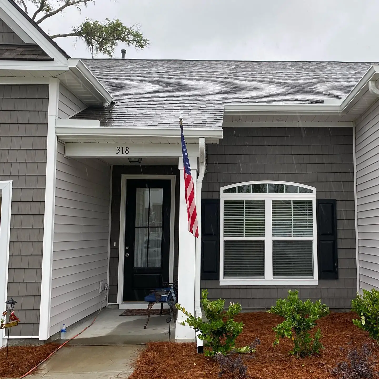Gray shingle-sided home with white gutters and downspouts at the front entry. Gutter Installation in Bluffton, SC by A&A Island Services