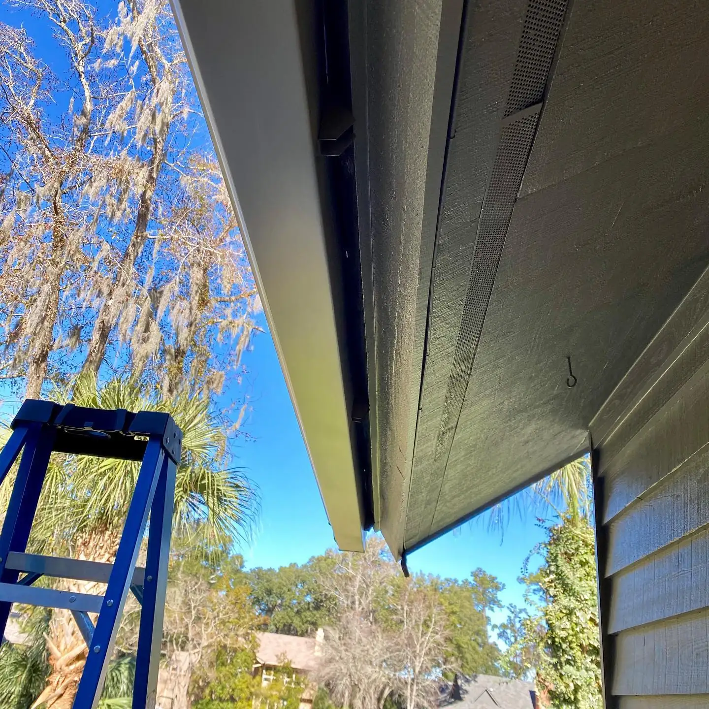 View from a ladder along a gutter and eave. Gutter Guards in Beaufort, SC by A&A Island Services