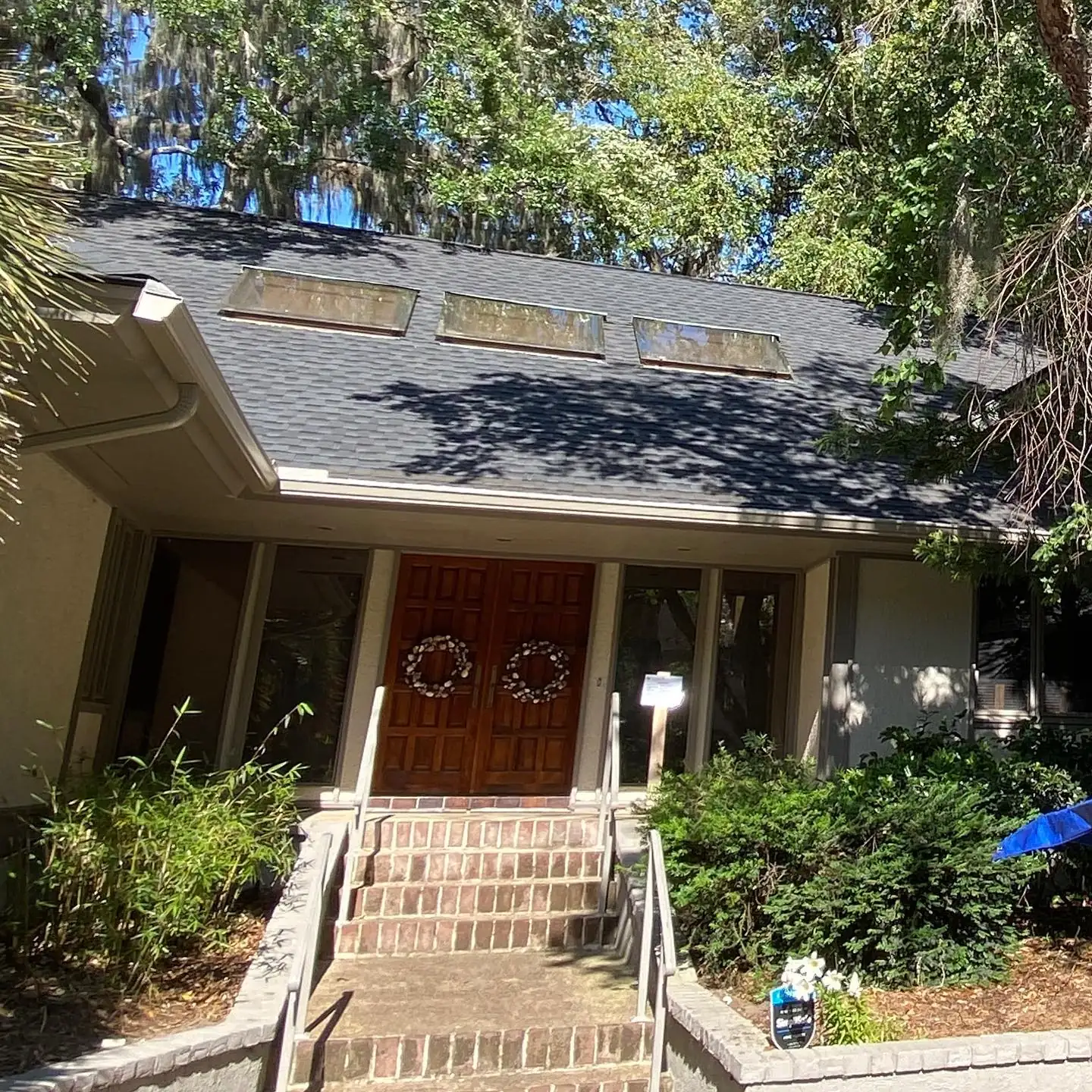 Home with skylights, wood double front doors and gutters among mature trees. Gutter Guards in Beaufort, SC by A&A Island Services