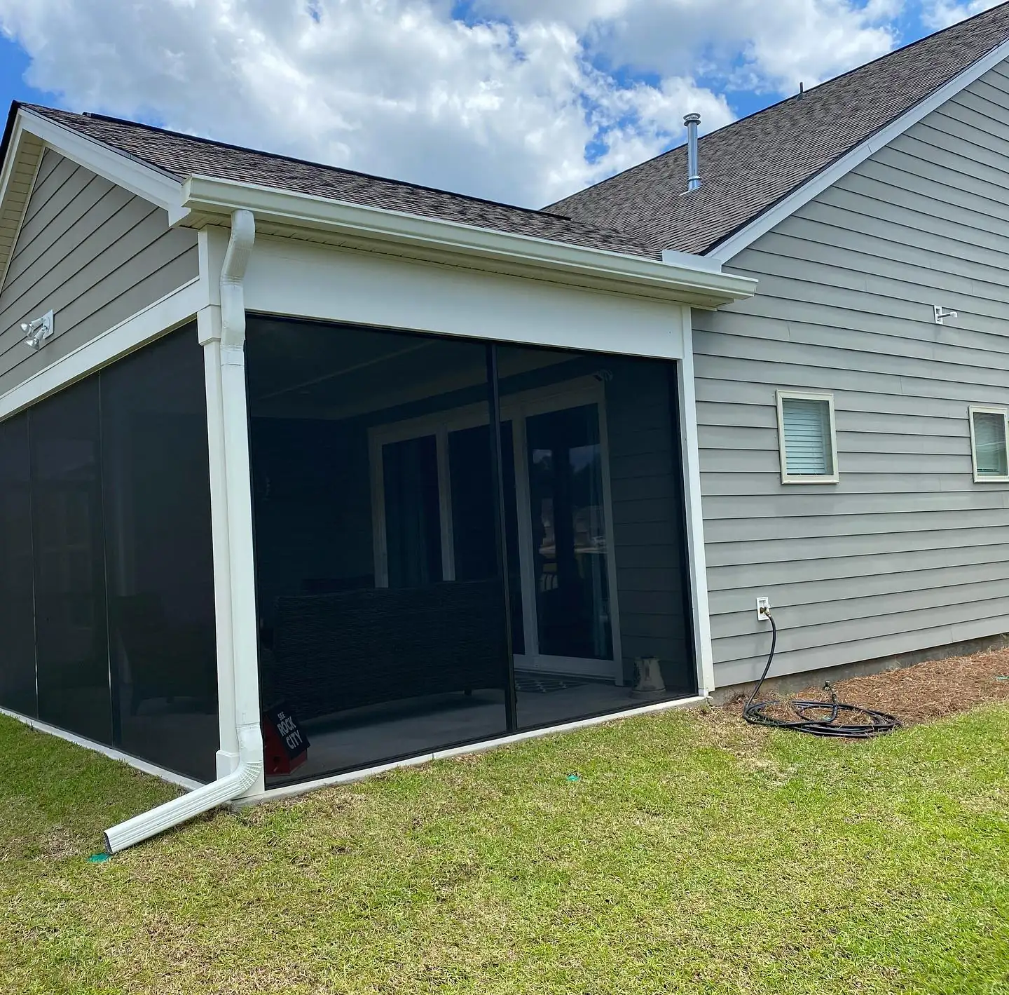 Screened porch on a gray home with a white gutter and downspout. Gutter services on Daufuskie Island, SC by A&A Island Services