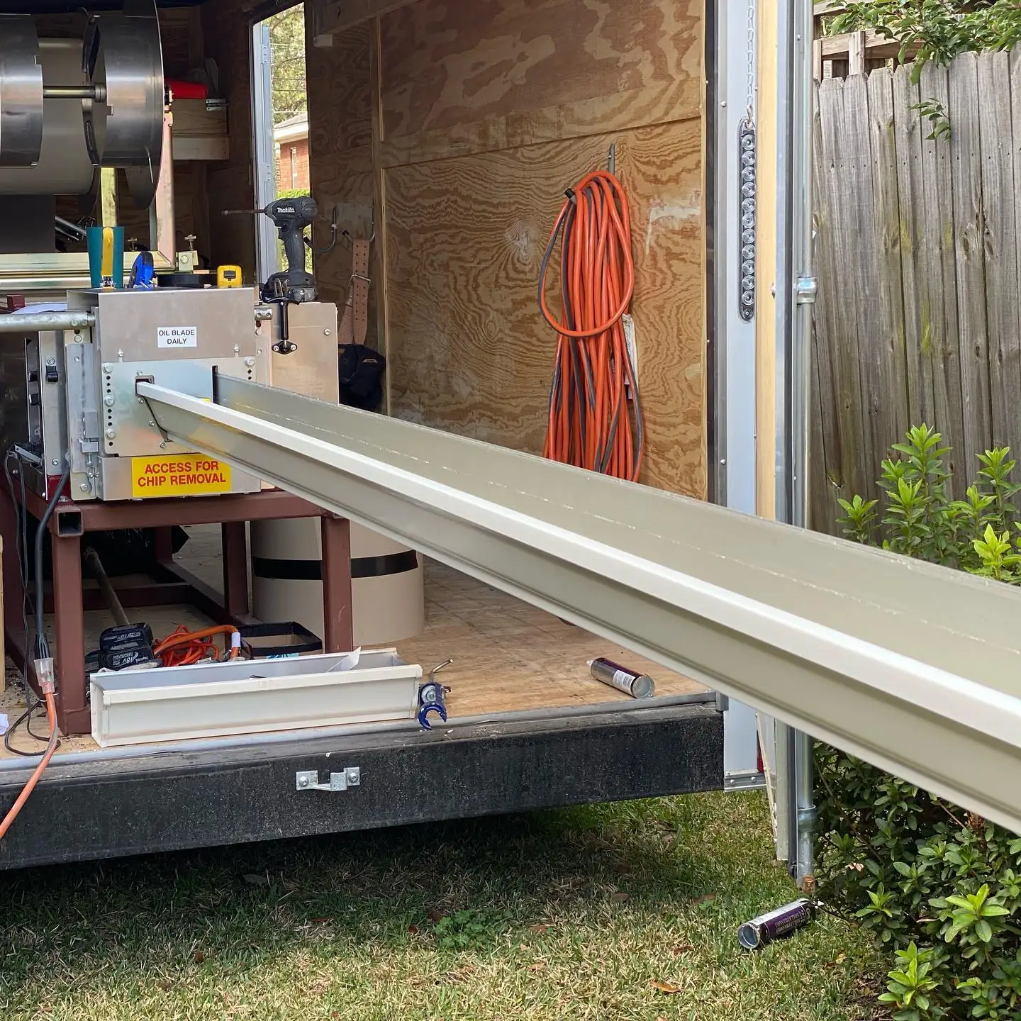 New seamless gutter running out of the forming machine in an A&A work trailer. Gutter cleaning and gutter installation in Bluffton, SC by A&A Island Services