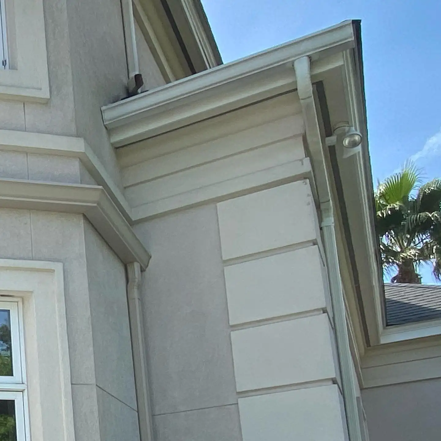 Stucco corner with a white gutter and downspout. Gutter Guards in Bluffton, SC by A&A Island Services