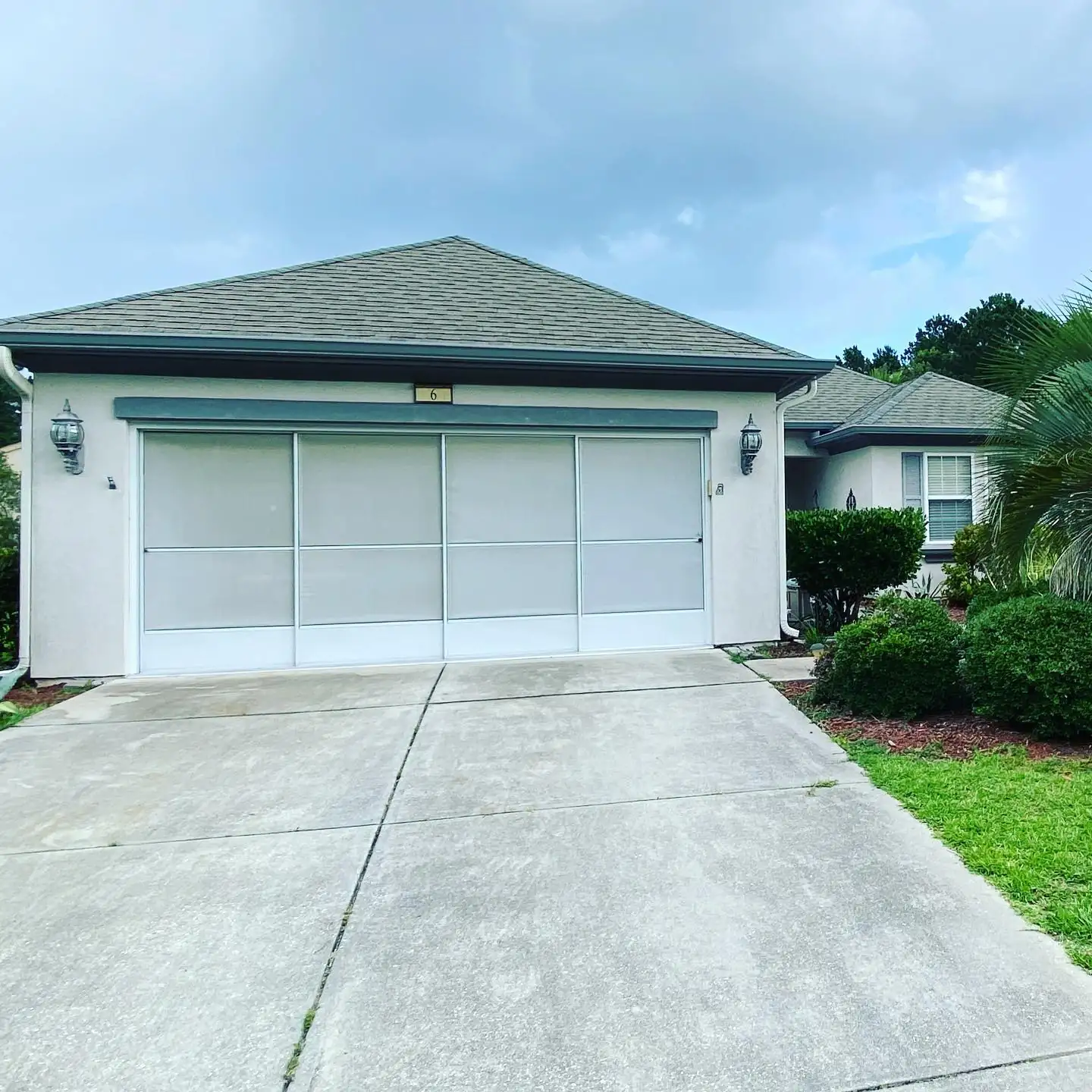 Two-car garage of a stucco ranch home with gutters along the roofline. Gutter Installation in Okatie, SC by A&A Island Services