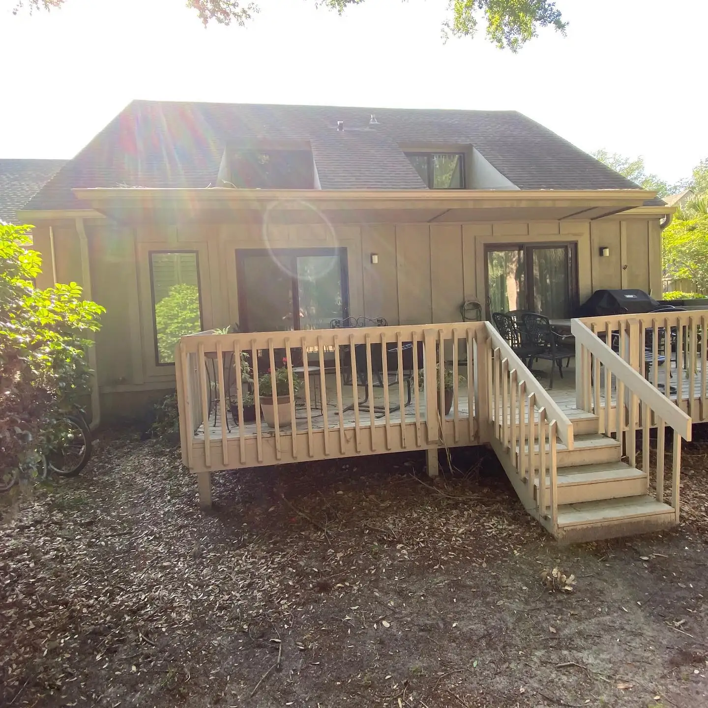 Tan home with a wood deck and stairs and gutters along the roofline. Gutter services in Palmetto Dunes, SC by A&A Island Services