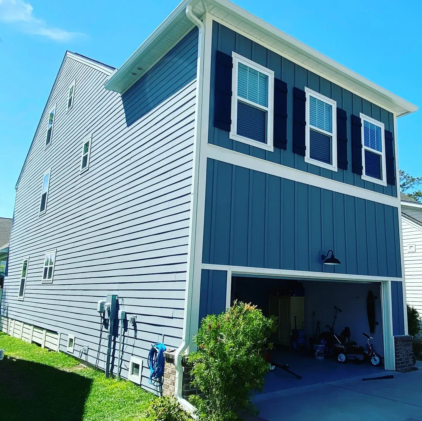 Side of a teal three-story home with white gutters and a long downspout. Gutter Installation in Okatie, SC by A&A Island Services