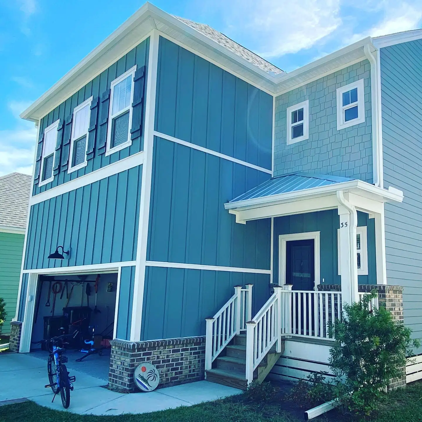 Teal two-story home with white trim, gutters and downspouts. Gutter cleaning and gutter installation in Bluffton, SC by A&A Island Services