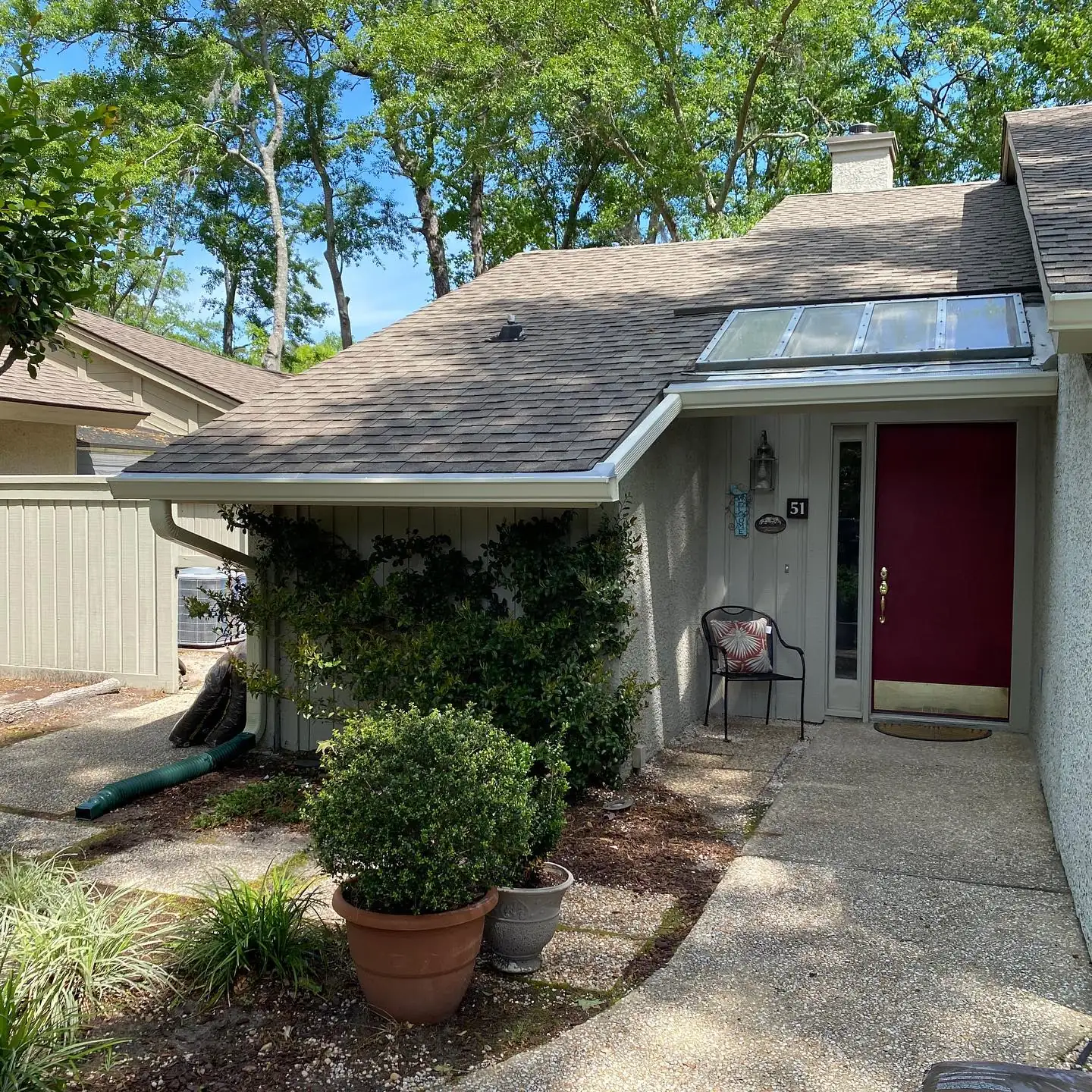 Front entry of a single-story villa with a red door and gutters. Gutter services in Pritchardville, SC by A&A Island Services