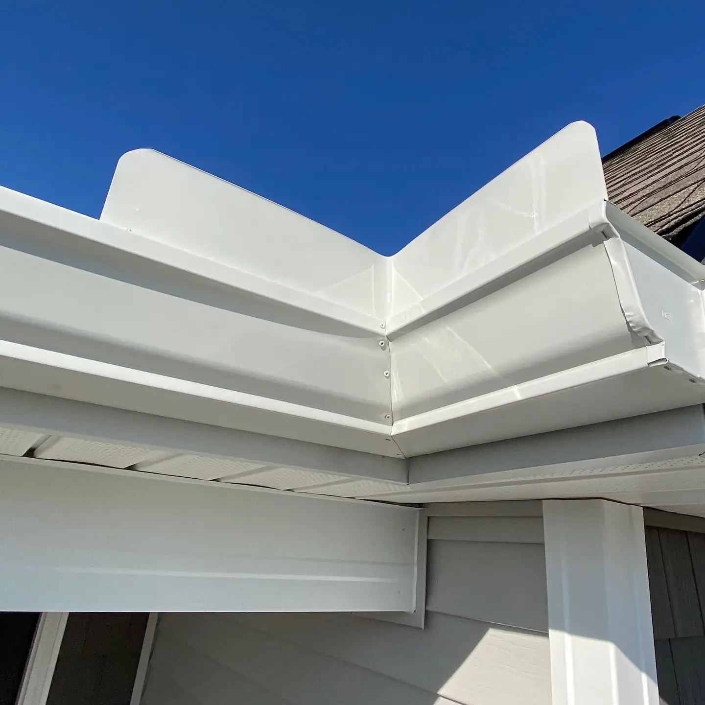 Close-up of a white mitered gutter corner against a blue sky. Gutter Guards in Bluffton, SC by A&A Island Services